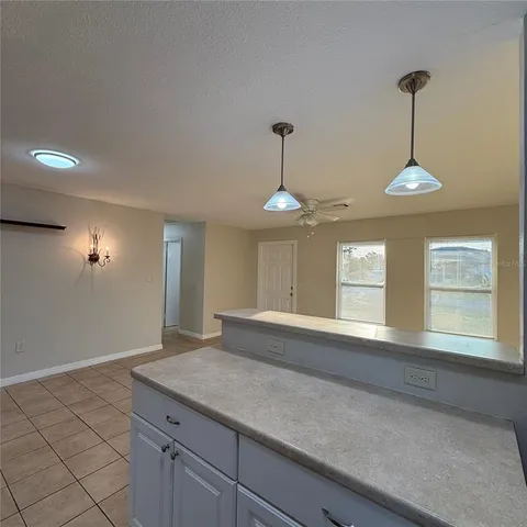 a view of an empty room with window and chandelier