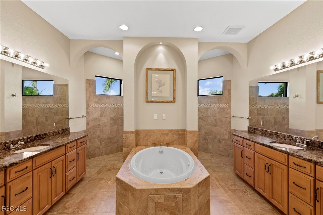6057 Calusa Rdg Trail Bokeelia, FL 33922 - Photo 17 of 45 a spacious bathroom with a tub double vanity sink and a mirror