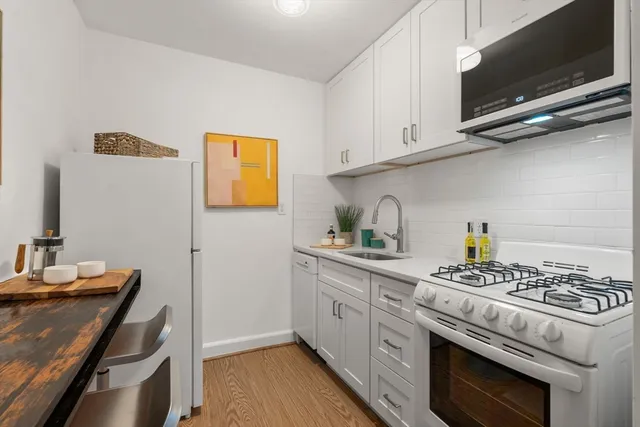 a kitchen with stainless steel appliances a stove a white cabinets and a sink