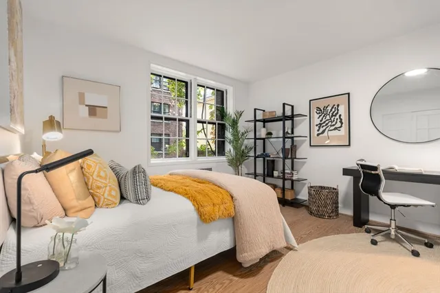 a bedroom with a bed a dresser and a large mirror next to a window