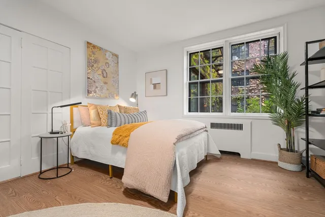 a bedroom with a bed and a potted plant next to a window