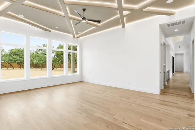 a view of an empty room with a window and wooden floor