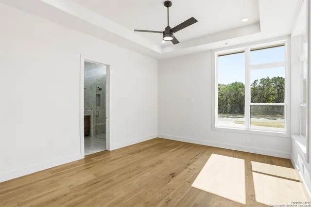a view of an empty room with a window and wooden floor