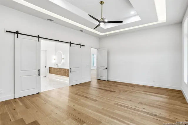 a view of an empty room with a window and wooden floor