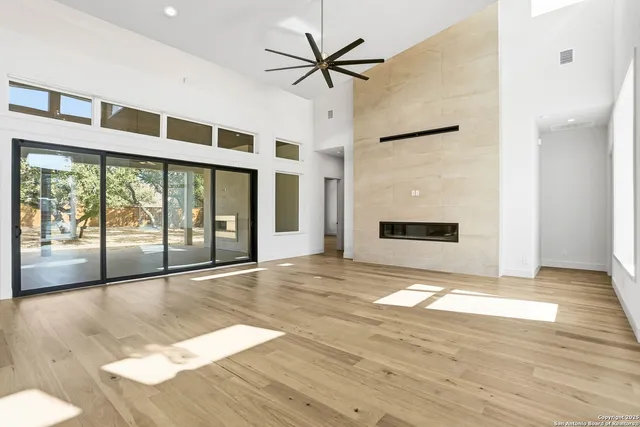 a view of an empty room with window and a kitchen view