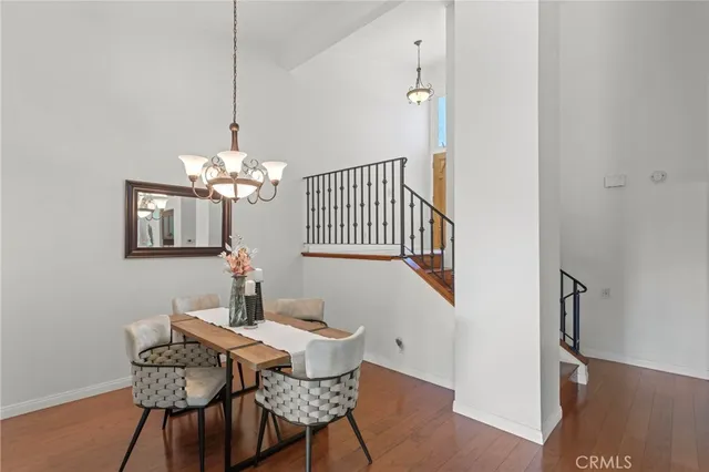 a dining room with furniture wooden floor a chandelier and a mirror