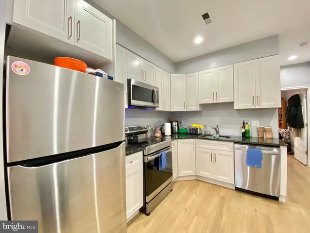 a kitchen with stainless steel appliances a refrigerator a sink and white cabinets