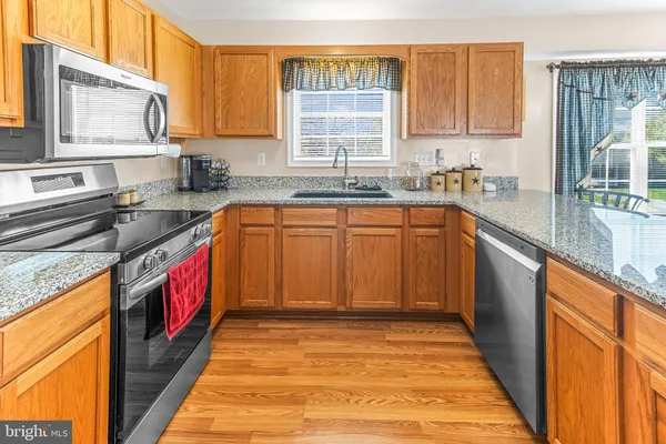 a kitchen with stainless steel appliances granite countertop a stove a sink and a microwave