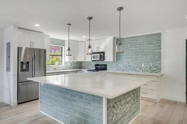 a view of a kitchen with kitchen island a counter top space stainless steel appliances and cabinets