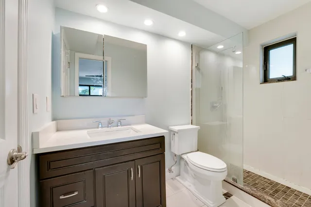 a bathroom with a sink a toilet a mirror and shower