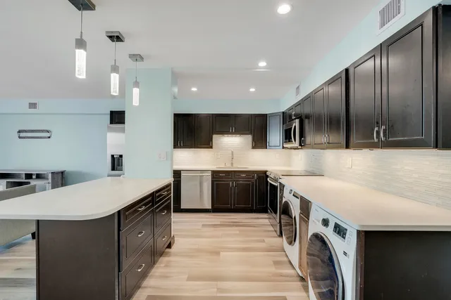 a large kitchen with stainless steel appliances granite countertop a sink a stove and a refrigerator