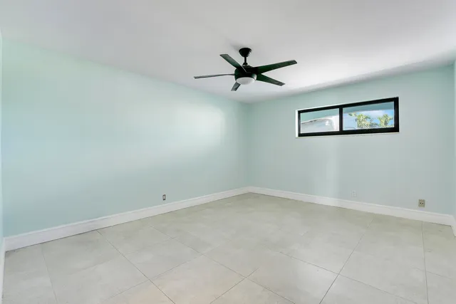 an empty room with a window and ceiling fan
