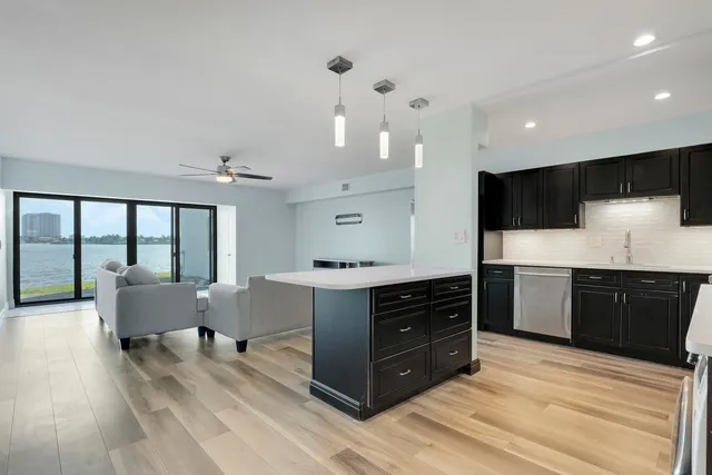 a large kitchen with stainless steel appliances a large counter top a stove and a wooden floors