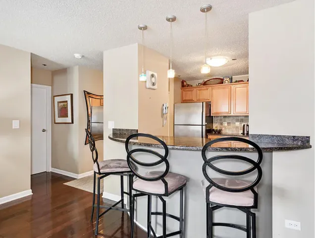 a kitchen with stainless steel appliances a refrigerator a stove a dining table and chairs with wooden floor