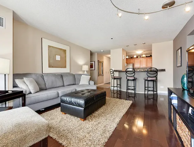 a living room with couches and kitchen view with wooden floor
