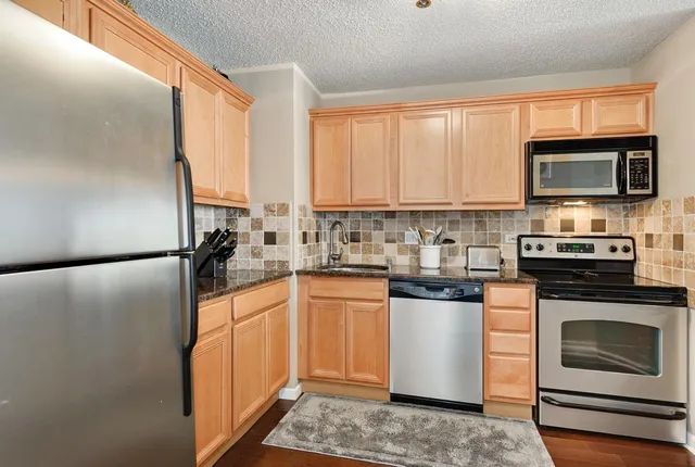 a kitchen with stainless steel appliances a stove sink microwave refrigerator and cabinets