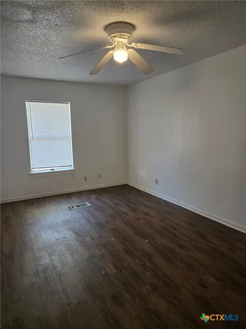 a view of a room with wooden floor and a ceiling fan