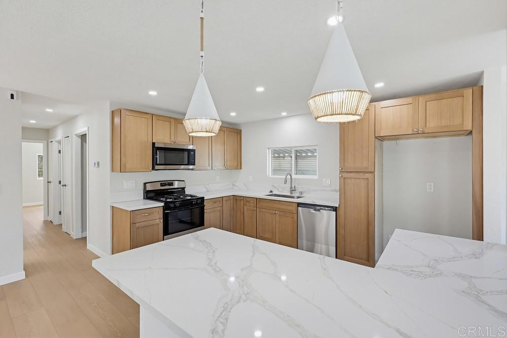 2400 Alpine Boulevard, Unit 8 Alpine, CA 91901 - Photo 6 of 19 a kitchen with stainless steel appliances kitchen island granite countertop a refrigerator a stove a sink a microwave oven with a dining table and chairs