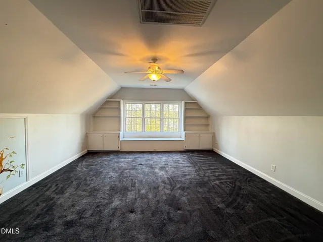 an empty room with windows and chandelier fan