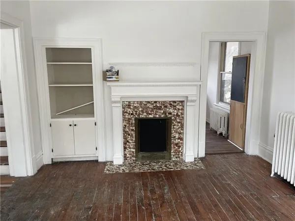 a view of a livingroom with wooden floor and a fireplace