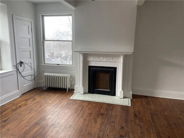 an empty room with wooden floor a fireplace and windows