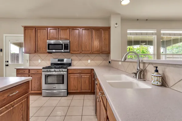 a kitchen with granite countertop a sink a stove top oven and cabinetry