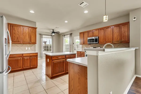 a kitchen with granite countertop a stove top oven a sink dishwasher and a refrigerator with wooden cabinets