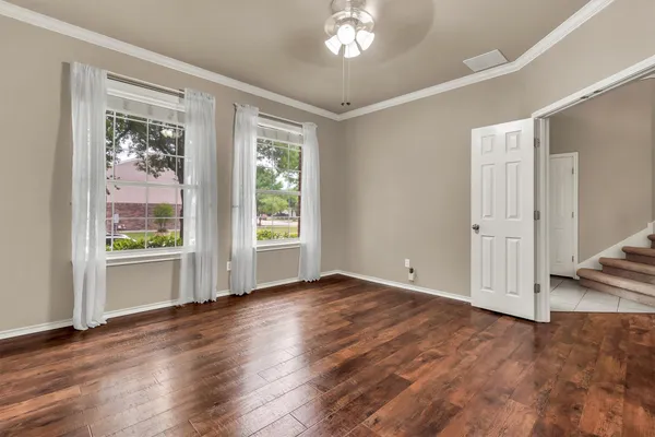 a view of an empty room with wooden floor and a window