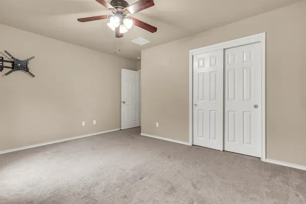a view of an empty room and chandelier fan