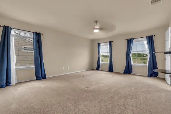 a view of an empty room with a window and a kitchen