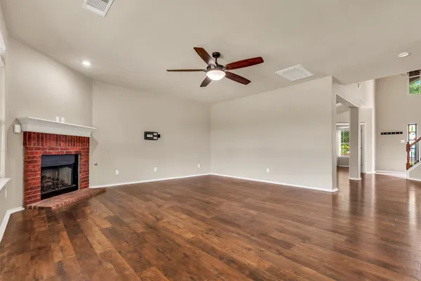 a view of empty room with wooden floor and fireplace