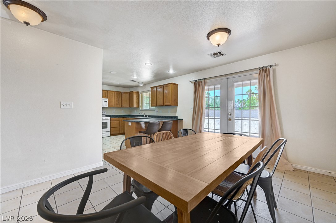1272 Liston Avenue Logandale, NV 89021 - Photo 61 of 61 An open floorplan seamlessly connects the dining area with a modern kitchen, bathed in natural light from the French doors.