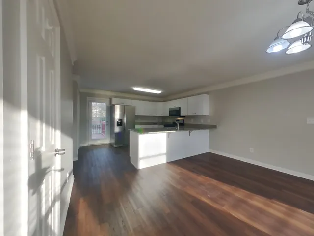 a view of a kitchen with a refrigerator and wooden floor