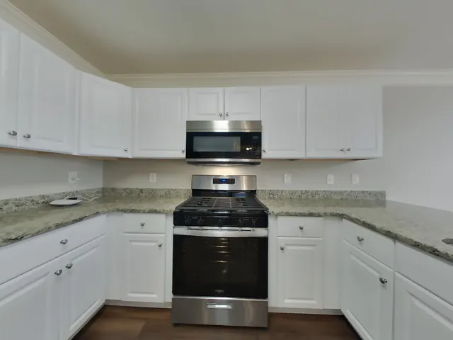 a kitchen with granite countertop white cabinets and stainless steel appliances