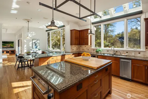 a kitchen with stainless steel appliances granite countertop a sink a stove and a wooden cabinets