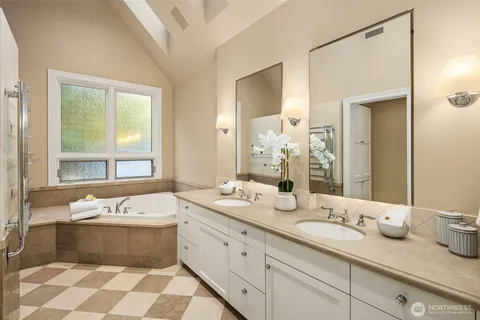 a bathroom with a double vanity sink large mirror and a bathtub