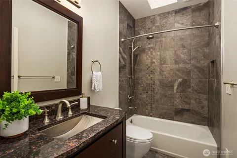 a bathroom with a granite countertop sink a toilet and shower