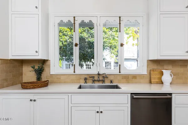 a kitchen with stainless steel appliances white cabinets a window and a sink
