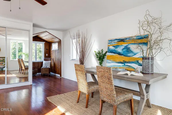 a view of a dining room with furniture one side kitchen view and wooden floor