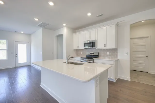 a kitchen with stainless steel appliances granite countertop a sink a stove and a refrigerator
