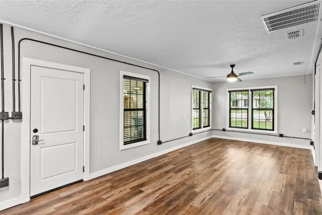 a view of an empty room with wooden floor and a window