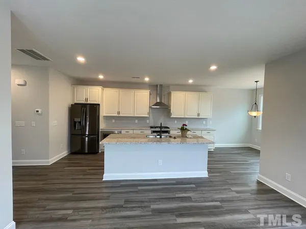 a view of a kitchen with kitchen island a sink wooden floor and stainless steel appliances