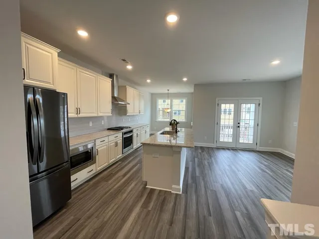 a kitchen with a refrigerator and wooden floor