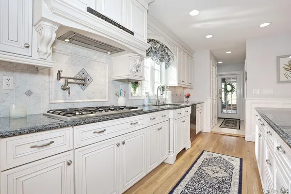 a large kitchen with granite countertop a stove and white cabinets