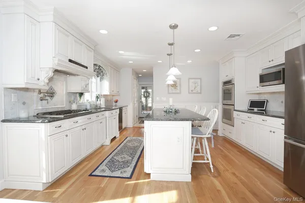 a large kitchen with granite countertop lots of counter space dining table and stainless steel appliances