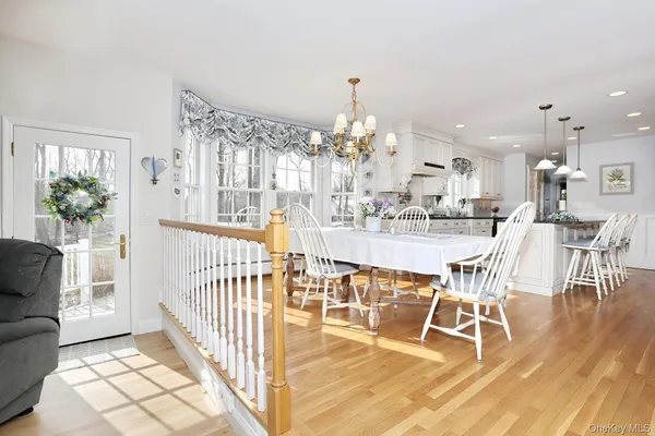 a dining room with wooden floor a chandelier a glass table and chairs
