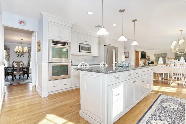 a large white kitchen with a large island oven a stove and a sink