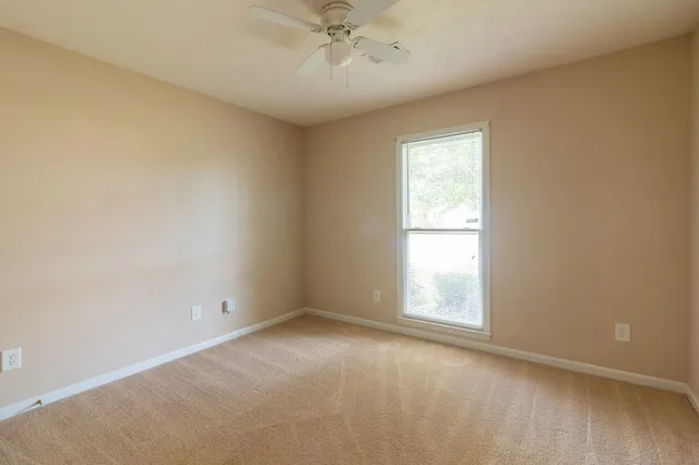 an empty room with a window and a fan