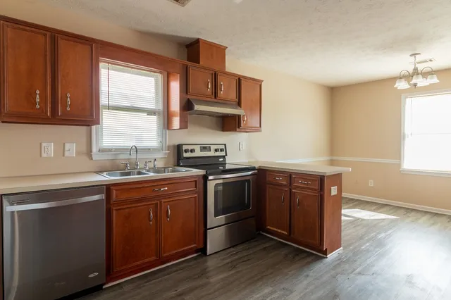 a kitchen with stainless steel appliances granite countertop wooden floors and sink