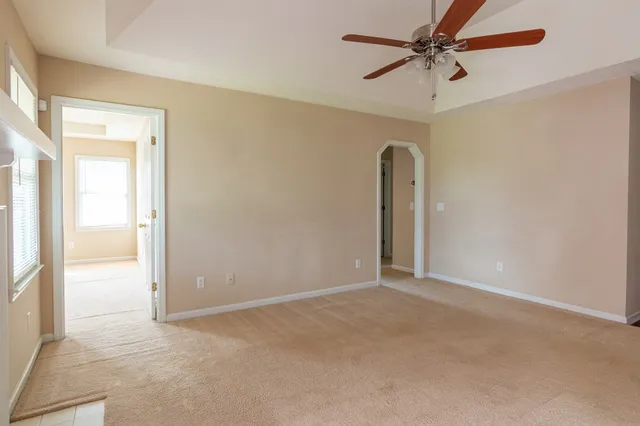 an empty room with a ceiling fan and a window